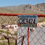 A Georgia car tag with the optional “In God We Trust” label hangs on a fence in Boquillas, Mexico.