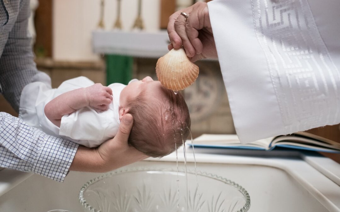 An infant being baptized with water sprinkled on their forehead.