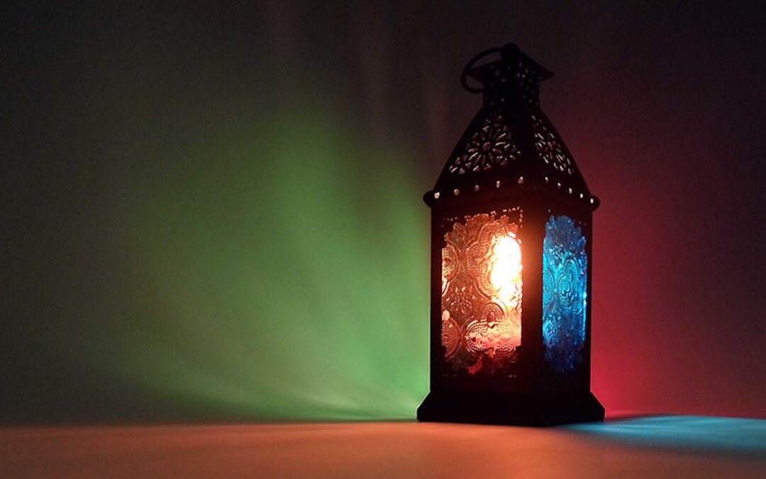 A lantern with several colored lenses illuminating a dark room with multiple colors.
