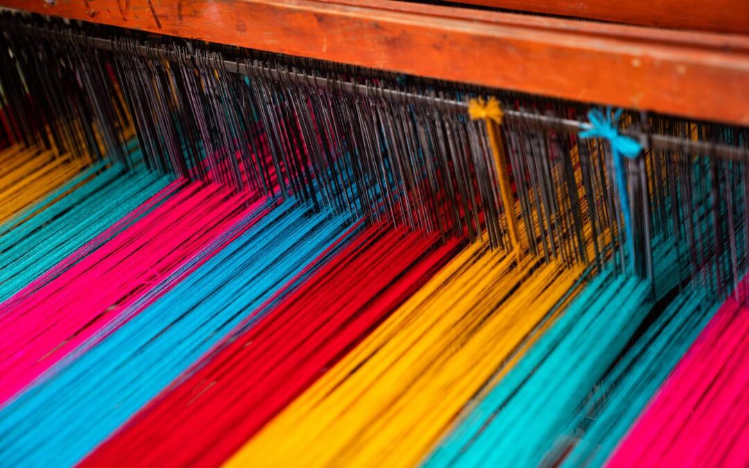 A weaving loom with colorful threads being fed into it.