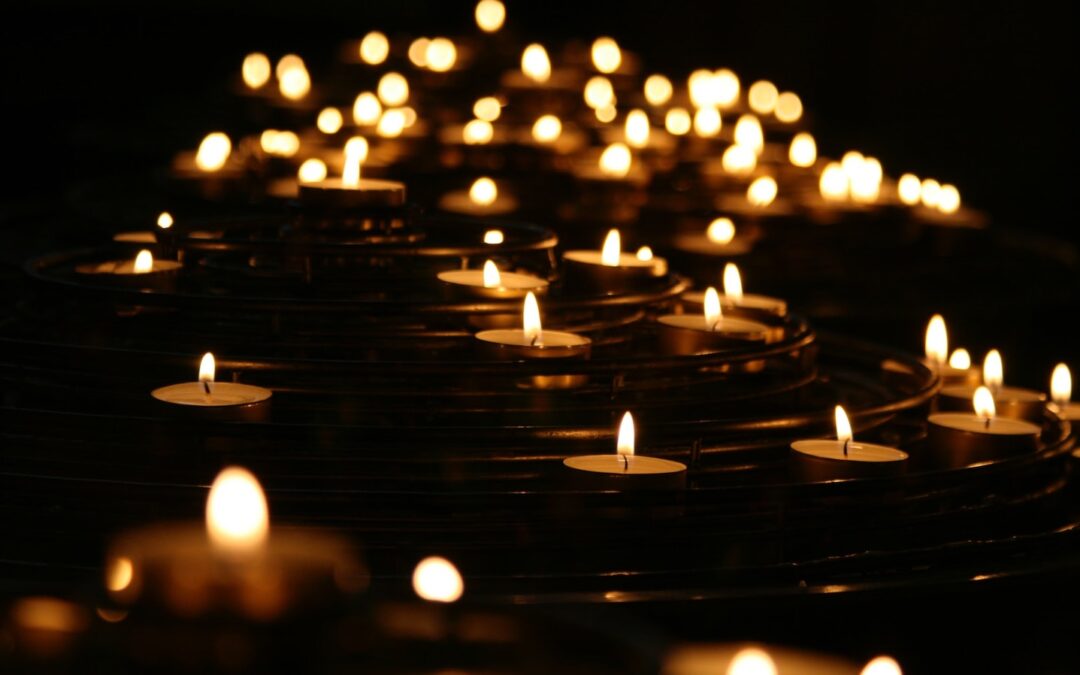 Many small candles lit in a dark room.