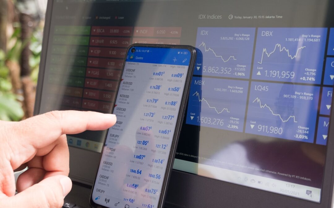 A computer and smartphone showing the position of various financial stocks.