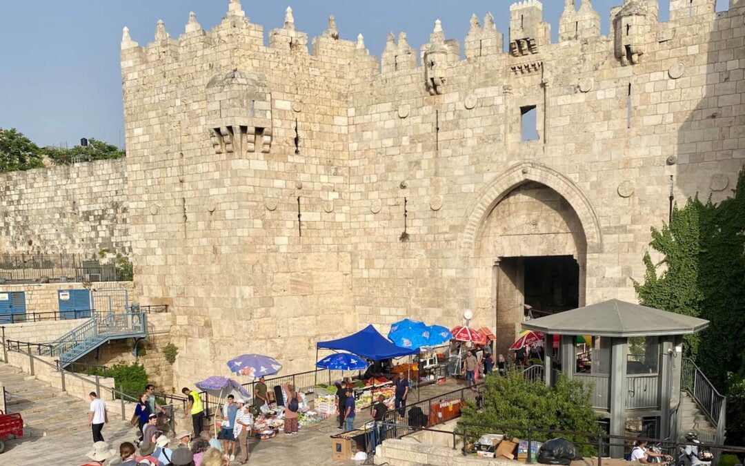 A small group of tourists and a few street vendors near the Damascus Gate in Jerusalem.