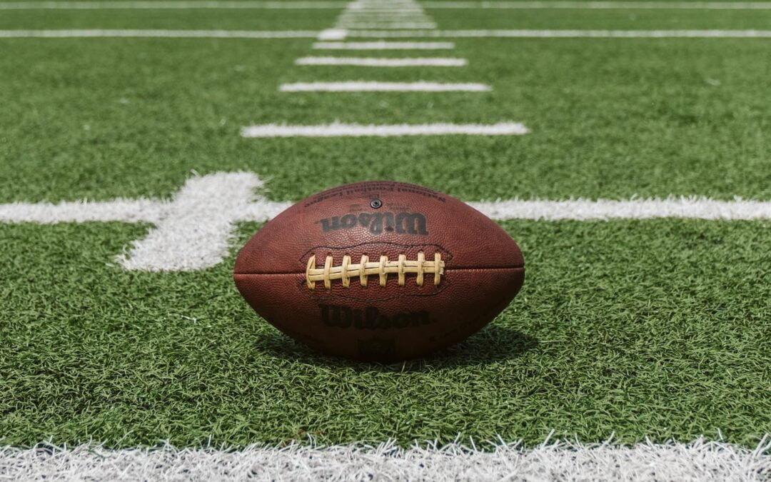 A leather football sitting on a football field.