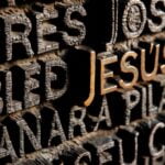 The name “Jesus” in gold lettering on a wall surrounding by other names.