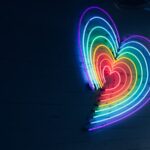 A neon light in the shape of a heart with rainbow colors.