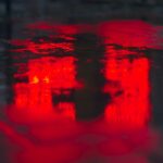 A puddle of water on the ground reflecting red light.