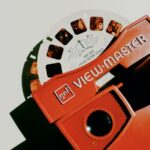 A red viewmaster sitting on a white surface.