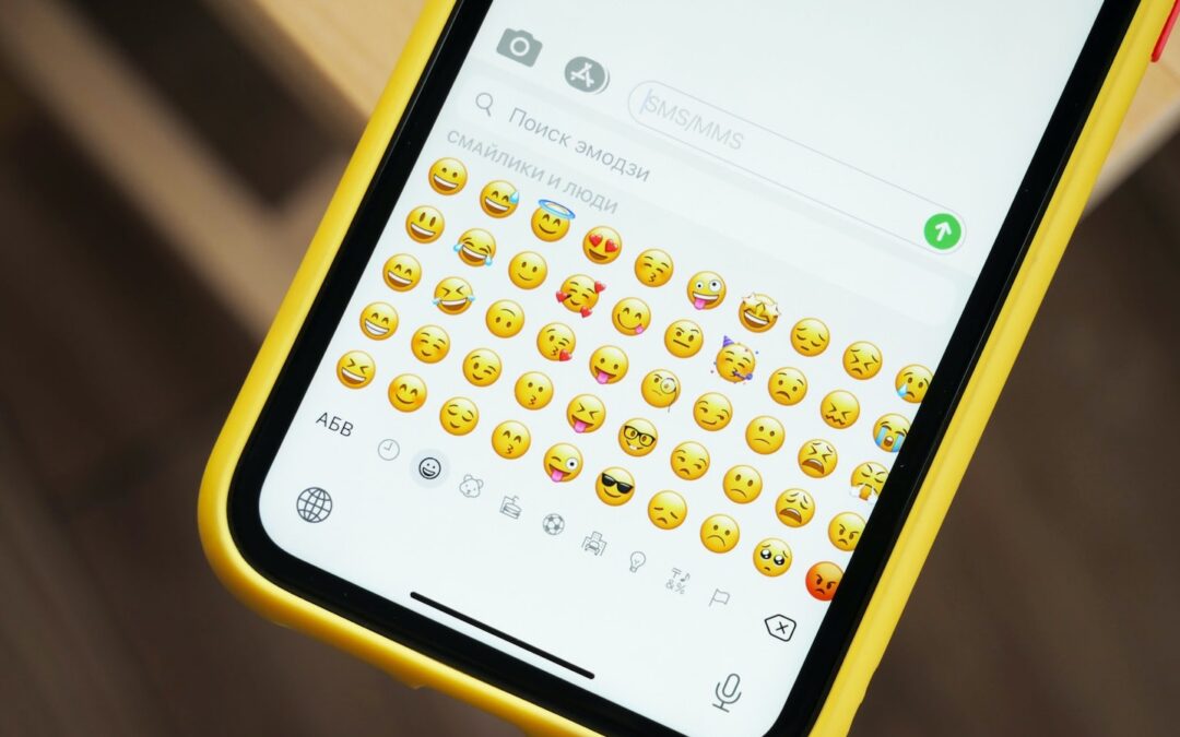 A smartphone with a yellow case and emojis on the screen.