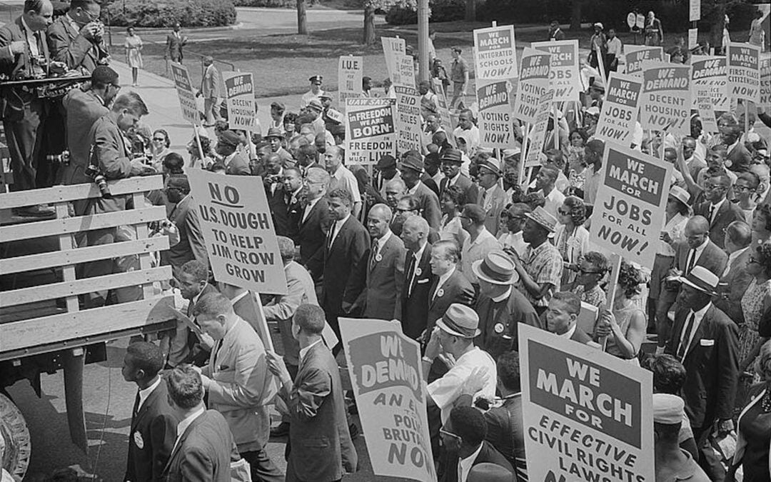 Civil rights leaders, including Martin Luther King Jr., surrounded by crowds carrying signs during the 1963 March on Washington.