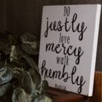 A painted sign displaying the words of Micah 6:8: “Do justly, love mercy, walk humbly.”