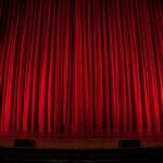 A red curtain on a large theater stage.