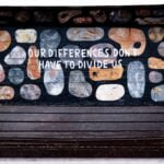 A mural on a cinder-block wall featuring rocks of various sizes with the words, “Our Differences Don’t Have to Divide Us.”
