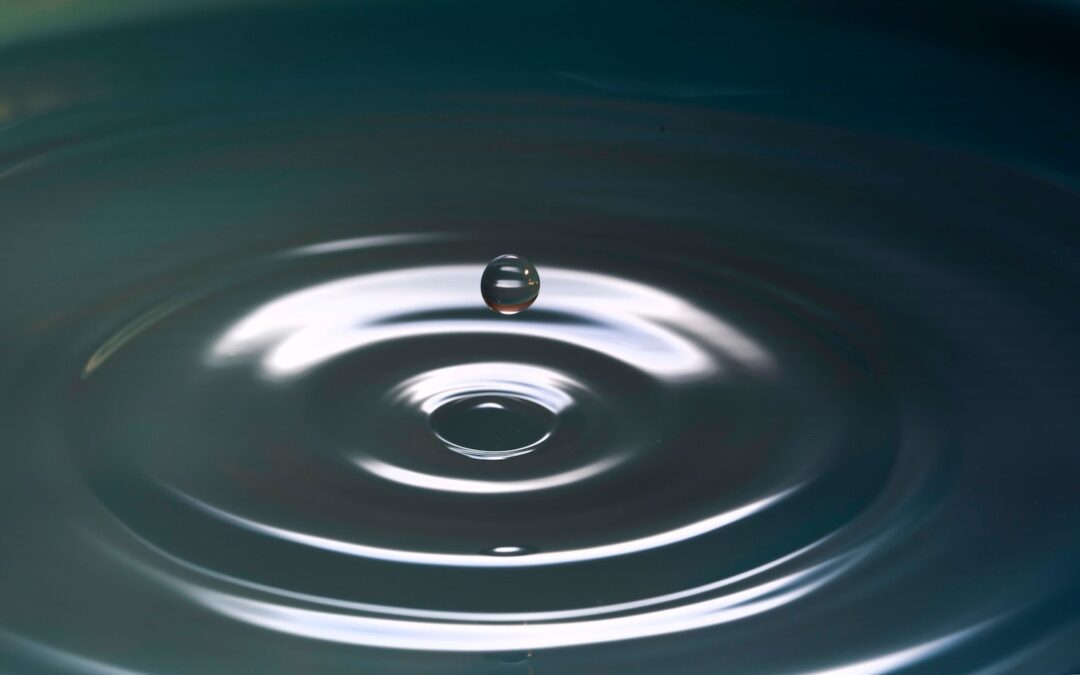 A water droplet landing on a pool of water and causing ripples.