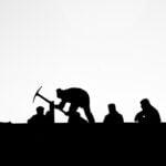 A silhouette of several people working outside.