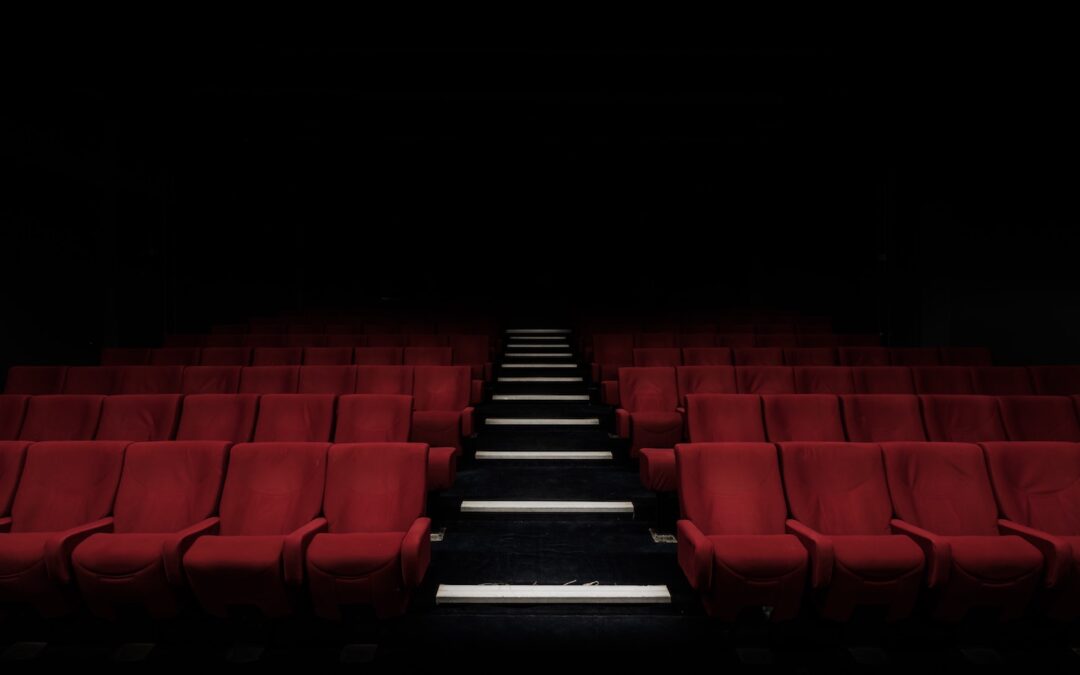 Rows of red seats in a theater seen from the front of the room with stairs in between the two sections of seats.