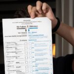 A person holding up a voting ballot.