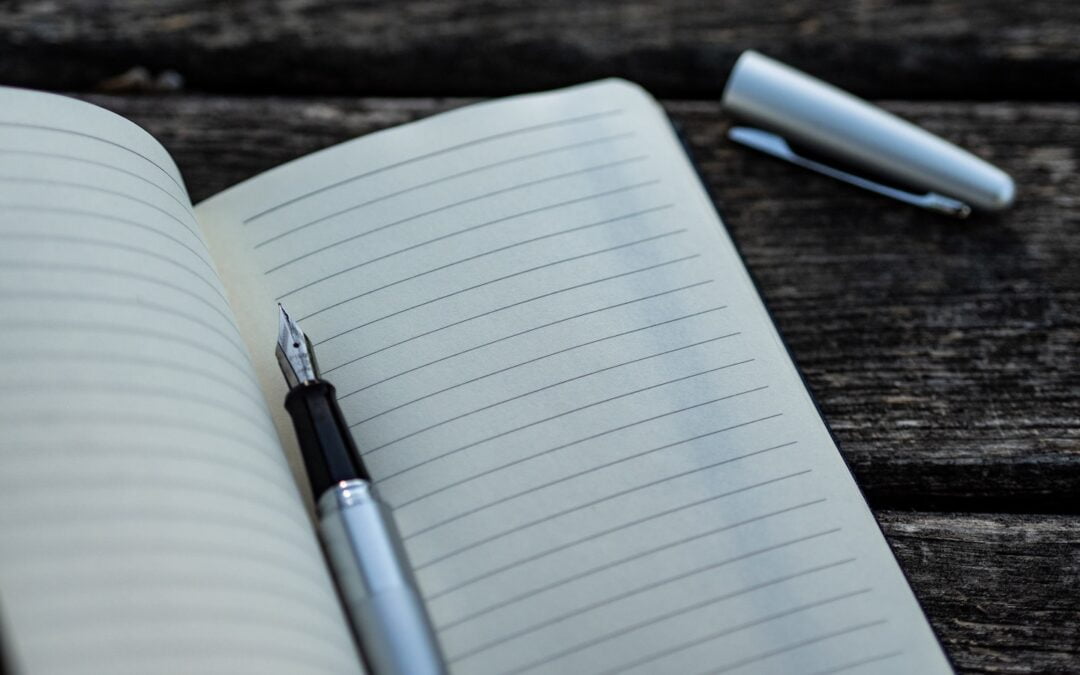 A blank, lined notebook page with a pen sitting on it.