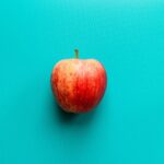 A red apple sitting on a blue table.