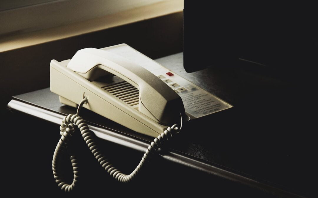 A corded telephone sitting on a desk.