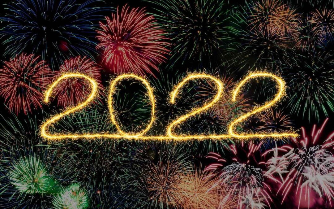 The year 2022 in yellow fireworks with lots of multi-colored fireworks in the background.