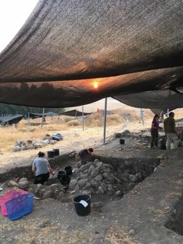 The sunrise seen rising over a tent erected over an archaeological dig site.