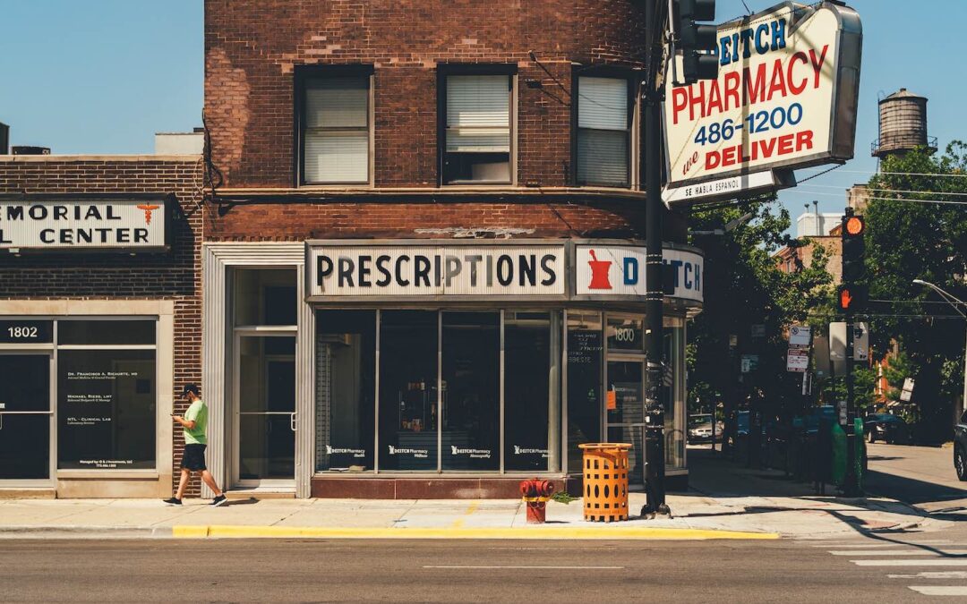 The exterior of a pharmacy in a red-brick building viewed from across a street.