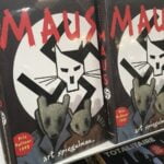 Two copies of the book ‘Maus’ by Art Spiegelman sitting on a shelf in a bookstore.