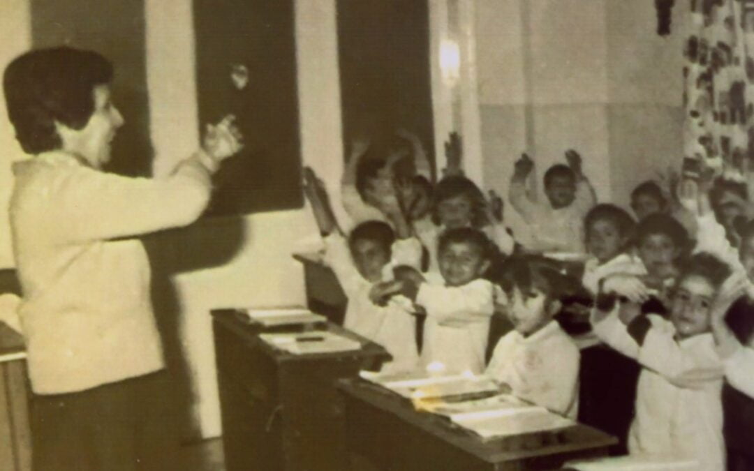 A black-and-white photo of a woman standing in the front of a classroom teaching students.