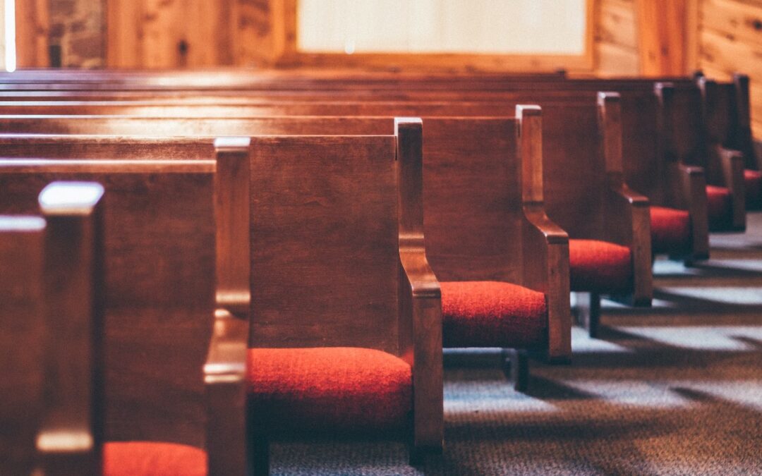 A row of pews with red cushions in a church worship space.