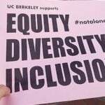 A person holding a piece of paper on which it says, “UC Berkley supports diversity, equity and inclusion.”