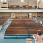 A woman standing in a pulpit looking out at an empty sanctuary.