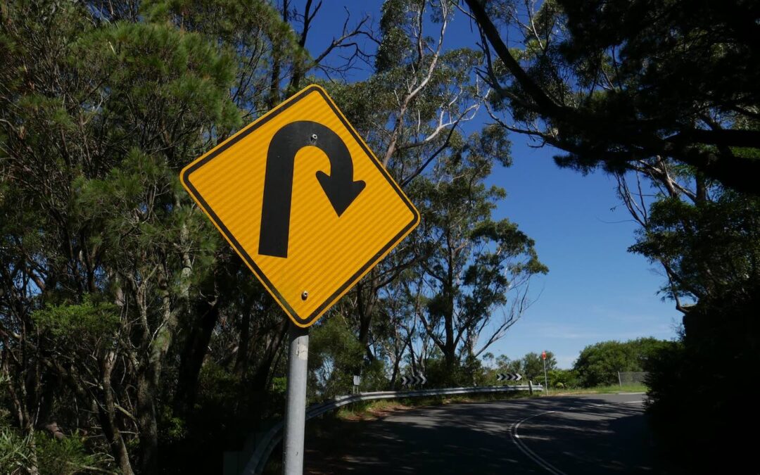 A yellow road sign indicating a u-turn.