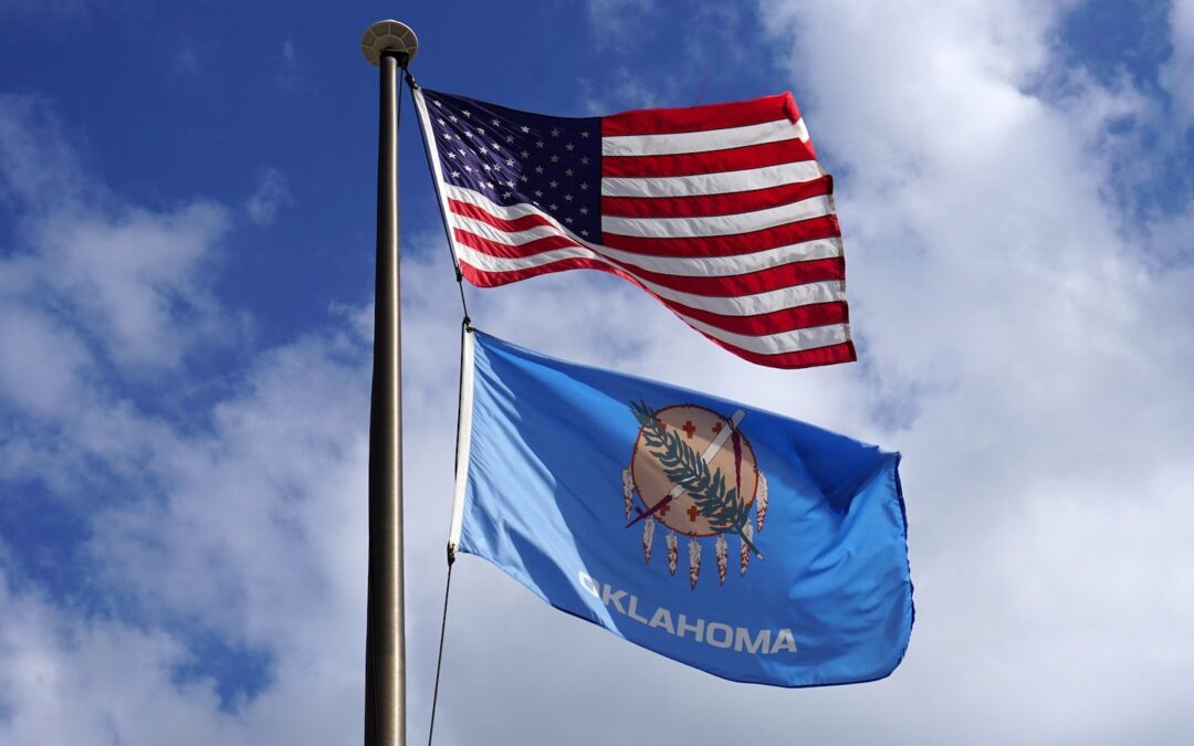 The U.S. flag and Oklahoma state flag flying on a single pole.
