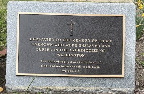 A metal plaque with a cross on it and words about what the location commemorates.