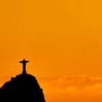 The Christ the Redeemer statue in silhouette at sunset.