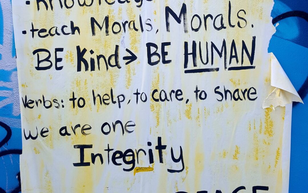 A flyer with ragged edges on a wall with various words about morals, kindness and integrity.