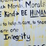 A flyer with ragged edges on a wall with various words about morals, kindness and integrity.