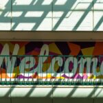 A wall with the word “welcome” painted on it in white letters with color patches surrounding it.