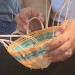 A person holding a woven basket that isn’t fully completed.