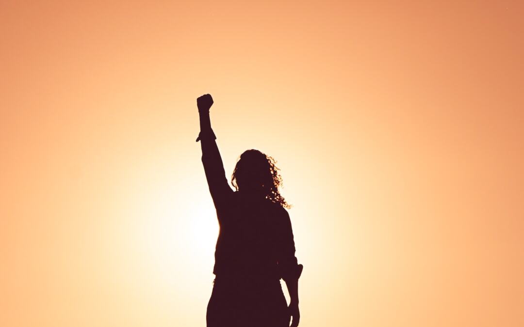 The silhouette of a woman with her arm raised in the air.
