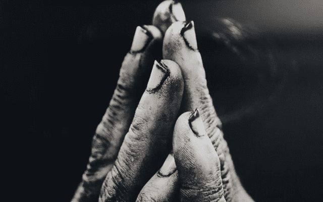 Hands poised in prayer with dirty nails