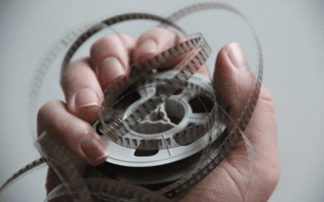 A hand holding an 8mm film movie.