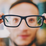 A blurred image of a man looking through a pair of glasses.