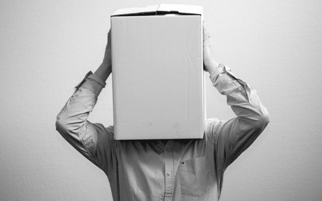 A grayscale picture of a man with a cardboard box over his head.