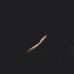 A man reaches his hand out in the darkness