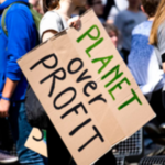 Woman holding a sign that reads, “PLANET over PROFIT.”