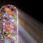 A photo of a stained glass window with the sun shining through.