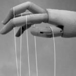 Wooden mannequin hand holding strings.