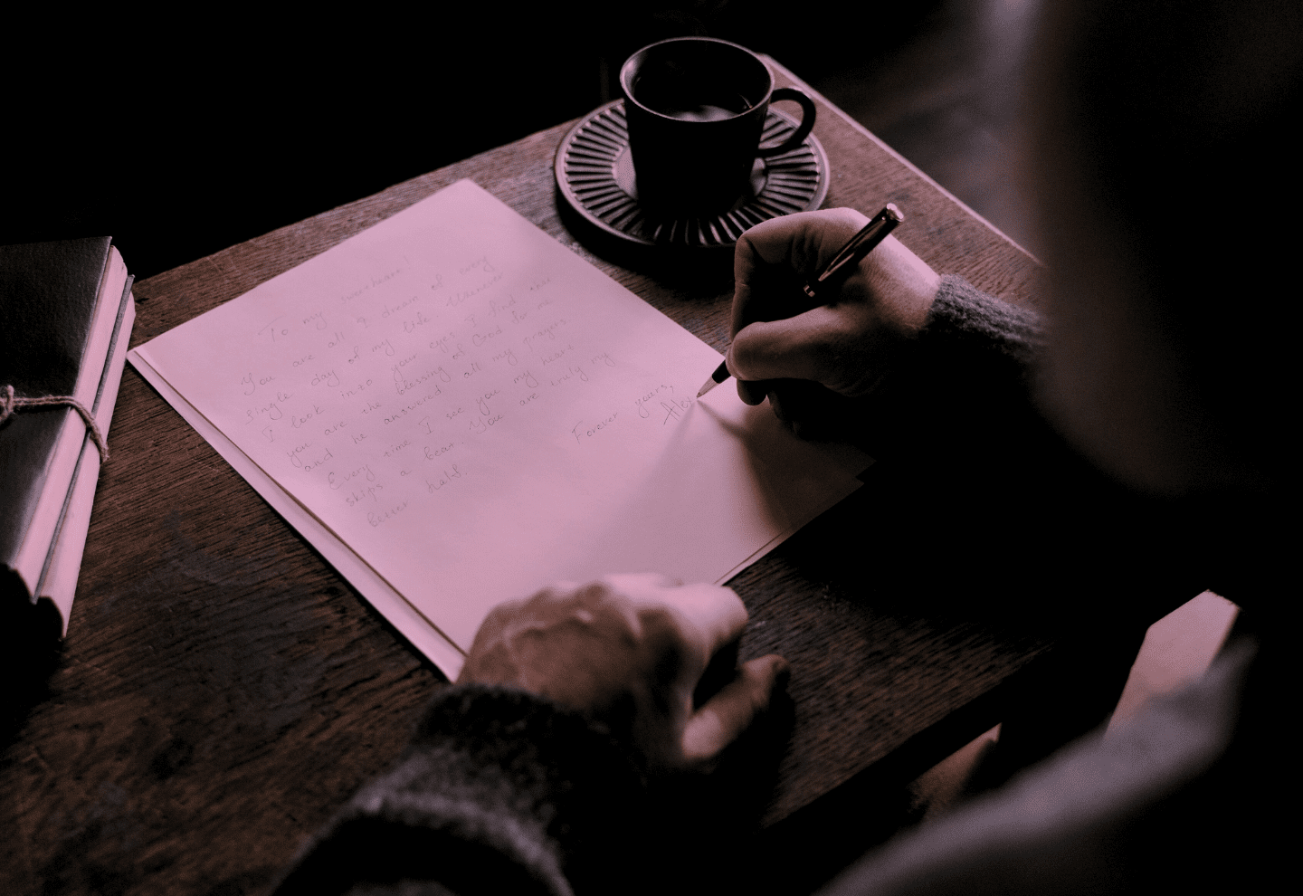 An older man writing a letter at a desk.